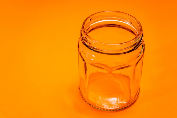 empty hexagonal glass flask isolated on orange bottom kitchen utensils - Консервированная тушёная говядина