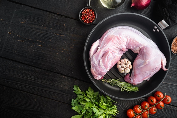 fresh raw rabbit with olive oil rosemary peppers sea salt onion set in cast iron frying pan on black wooden table background top view flat lay with copy space for - Мясной пасхальный стол: кролик, тушённый в сметане