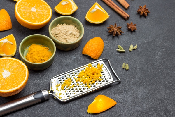 grated orange peel on grater sliced orange and spices on table black background top view - Маковая пасха с апельсиновым конфитюром