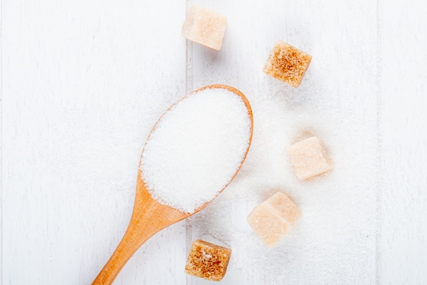 top view of a wooden spoon with white sugar and lump sugar on white background - Драники с апельсиново-клюквенным соусом