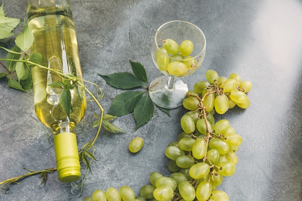 top view of bottle white wine green vine wineglass and ripe grape on vintage gray stone table backgr - Мясной пасхальный стол: кролик, тушённый в сметане