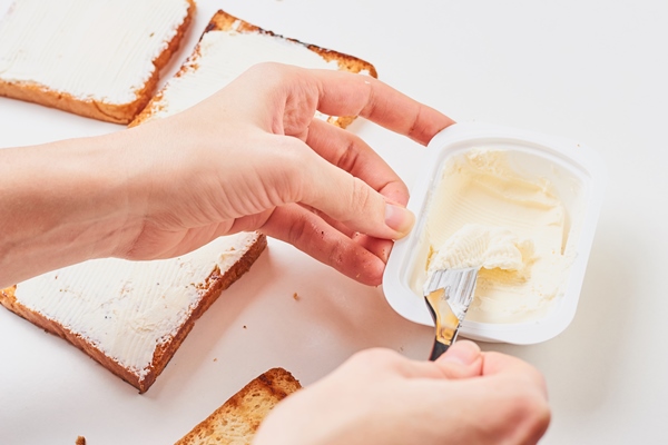 woman hand make sandwich spred toasted bread with a cheese - Консервирование пищевых продуктов