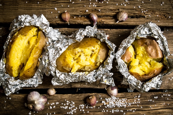 baked potatoes in foil on a wooden table 1 - Печёный на углях картофель с начинкой