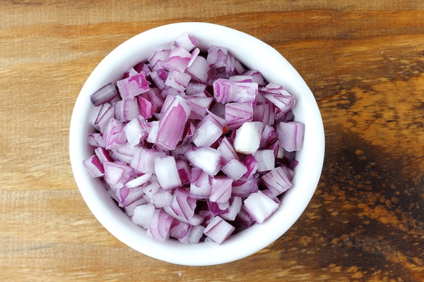 chopped raw red onion in white ceramic bowl over rustic wooden table close up view - Тюря "Сибирская"