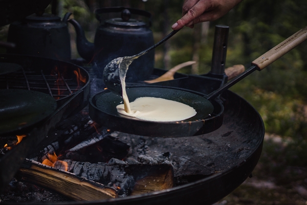 closeup of a person cooking pancakes over the campfire outdoors - Организация трапезы в походе: хранение продуктов, походная кухня, утварь, меню