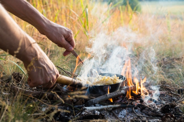 cooking food in pan on camping fire - Питание в походе