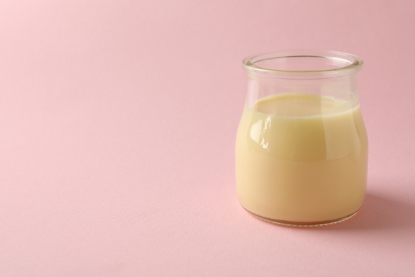 glass jar with condensed milk on pink background - Тюря детская молочная