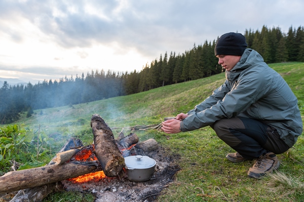hiker prepares food at a stake in a hike in the mountains at altitude - Туристический омлет в пакете