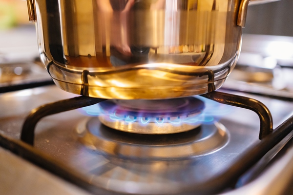 saucepan in a fire on the burner of the gas stove a stove uses combustible or natural gas from the city gas network or liquefied gas as fuel the energy crisis and rising energy prices - Пшённая каша с луком и чесноком