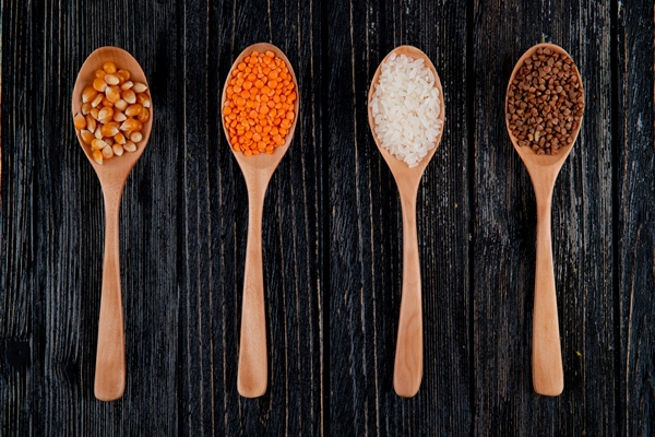 top view of different types of groats and seeds in wooden spoonscorn seeds red lentil rice and buckwheat - Каша "Остатки сладки"