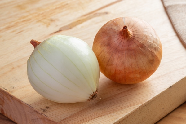two onions on a light brown wood cutting board - Картошка с тушёнкой из полуфабриката