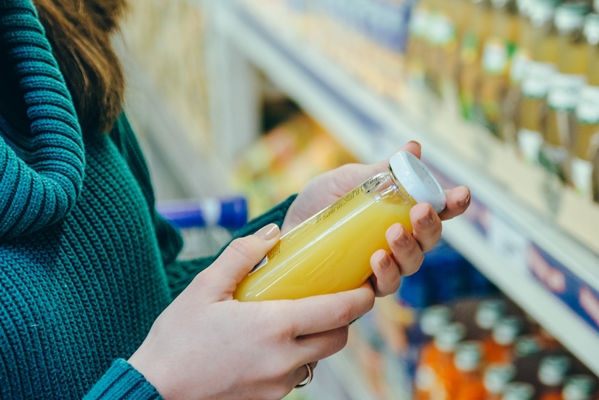woman in store read ingredients of juice grocery shopping copy space - Как перестать выбрасывать продукты и сократить расходы