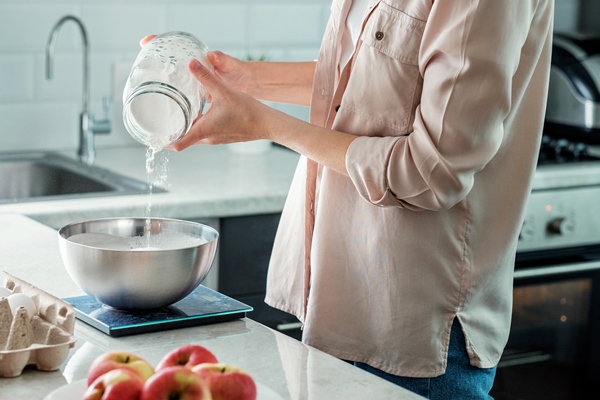 a woman in the kitchen adds rice flour to a bowl for making apple pie cooking - Постная шарлотка на апельсиновом соке