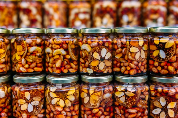 bee honey with nuts in glass cans on counter of market - Мёд с орехами