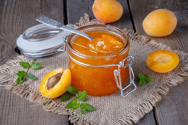 jam from apricots in a glass jar on an old wooden table - Абрикосовое варенье