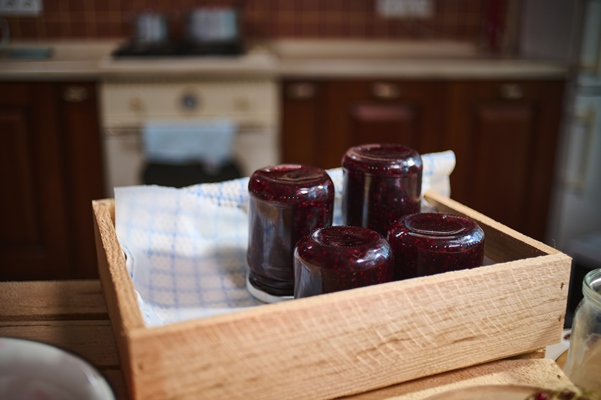 jars with berry jam stacking upside down on wooden crate standing on kitchen island - Клубничное варенье
