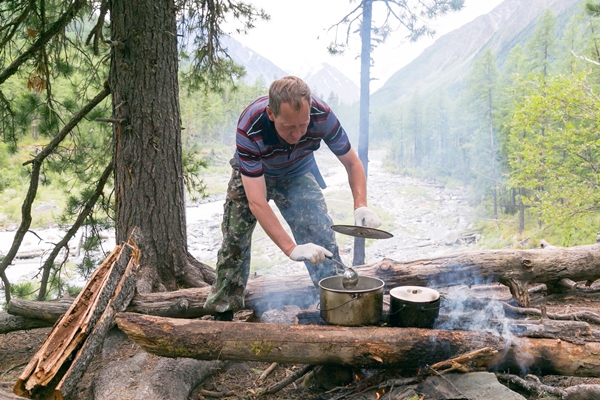 the man is cooking food at the stake in the forest - Макароны с тушёнкой и лесными грибами на костре