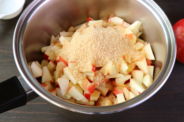 unrefined sugar added into the pot of diced apples for making apple compote - Яблочное варенье с гвоздикой