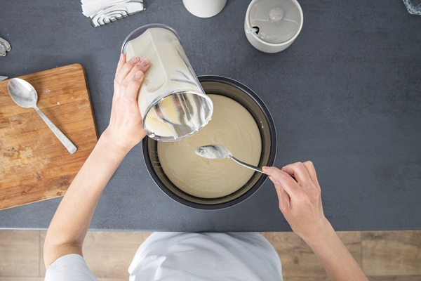 woman pouring dough into baking dish top view flat lay - Постная шарлотка на апельсиновом соке