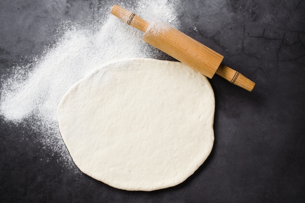 rolled dough baking flour and rolling pin on a dark blackboard - Постный маковый рулет с мёдом и изюмом