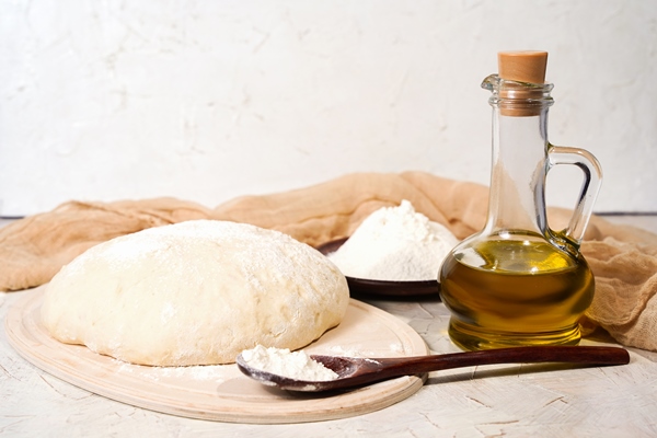 ball of dough on the kitchen table olive oil in a bottle with copy space kneading pizza dough rustic bread homemade high quality photo - Пицца "Маргарита"