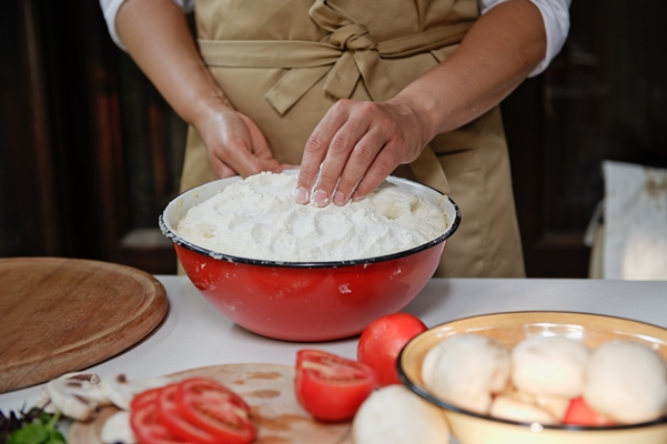 closeup of female pastry chef hands kneading yeast dough for pizza in a vintage enamel bowl in a rustic kitchen - Пицца постная