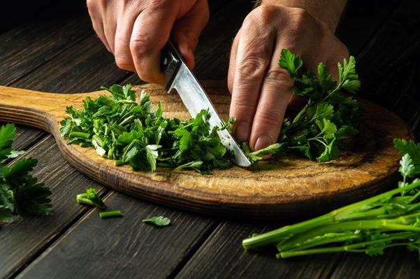 cook cutting green parsley on a cutting board with a knife - Постная пицца на пресном тесте