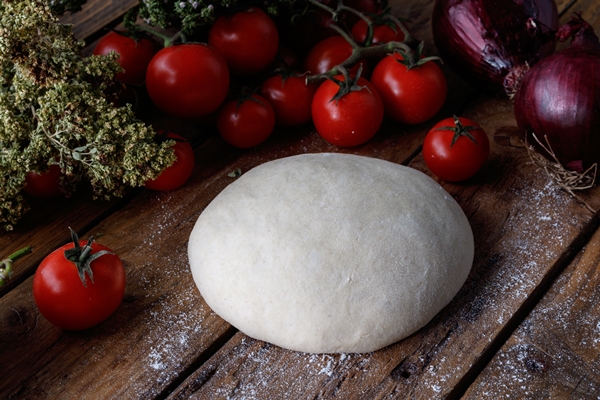 lump of dough on a wooden table surrounded with tomatoes and onions - Пицца "Карри"