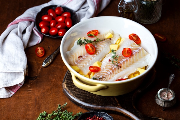 raw cod fillet with potatoes and tomatoes in ceramic baking dish - Белая рыба, запечённая с овощами