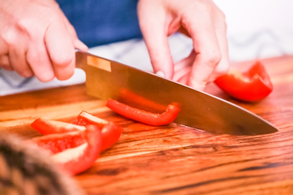 step by step slicing red bell pepper on a wood cutting board - Постная пицца на пресном тесте
