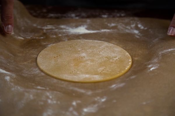 the rolled dough in the form of a circle lies on parchment on a dark background high quality photo - Постная пицца на пресном тесте