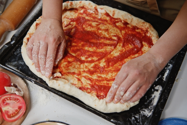 top view of pizzaiolo chef putting feta cheese on the sides of the dough while preparing tasty pizza in rustic kitchen - Пицца постная