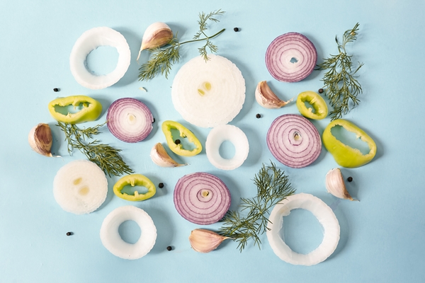 top view of raw onion rings with yellow pepper peppercorns garlic and dill on a blue surface - Картофельные зразы с овощной начинкой