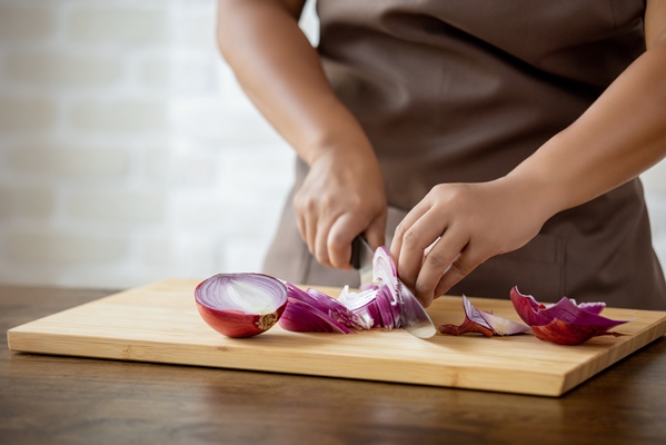 woman hands slicing red onion in kitchen - Постная пицца на пресном тесте