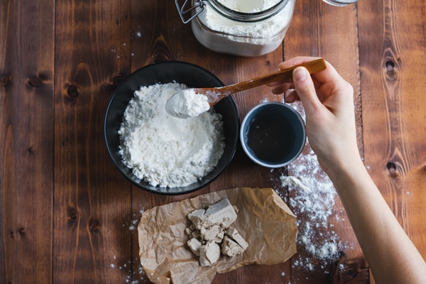 a woman s hand adding flour to make sourdough bakery concept - Пицца постная на тонком тесте
