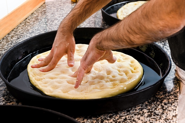 chef stretching pizza dough in a tray - Пицца "Сицилийская"
