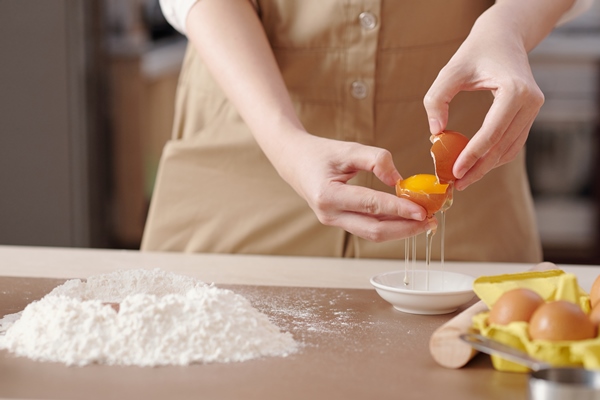 hands of young woman separating egg yolks from egg whites when making dough - Печенье "Хворост"