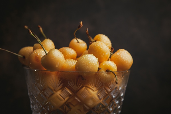 rainier cherries in a tall fruit bowl on a dark brown close up - Пикули из фруктов и ягод
