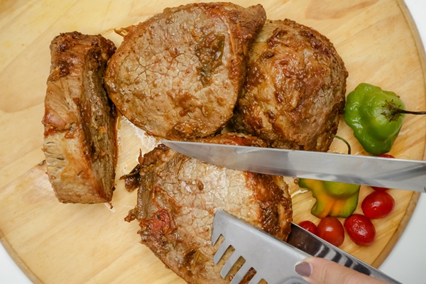 slice of pot cooked meat on wooden board with knife and cutlery - Тавранчук из говядины