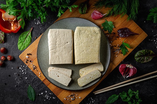 sliced tofu soy cheese on a cutting board with basil spices and vegetables - Пицца постная на тонком тесте