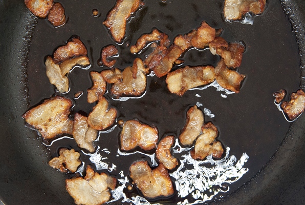 small pieces of bacon are cooked in a pan top view - Крупник белорусский