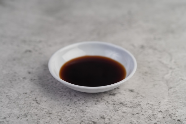 the black sauce in a small white cup placed on the cement floor - Пицца с морепродуктами