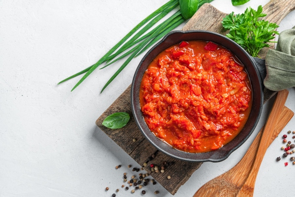 tomato sauce in a frying pan and fresh herbs on a gray background - Пицца постная на тонком тесте