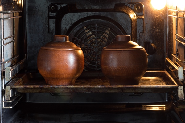two clay pots on the pan in the oven - Тавранчук из говядины