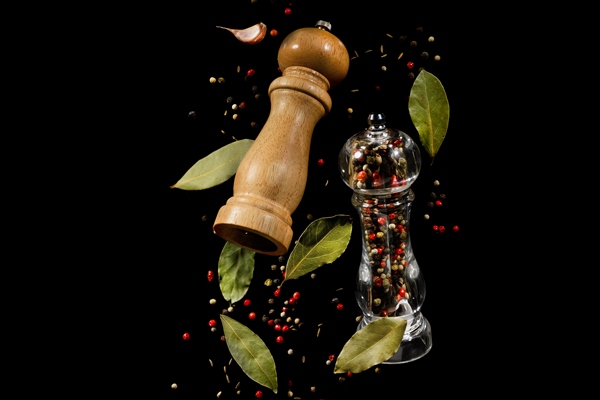two spice mills with peppercorns and laurel leaves flying on black - Тавранчук из говядины
