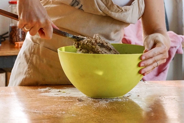 young woman kneading dough for homemade whole grain rye bread in green plastic bowl - Калитки карельские