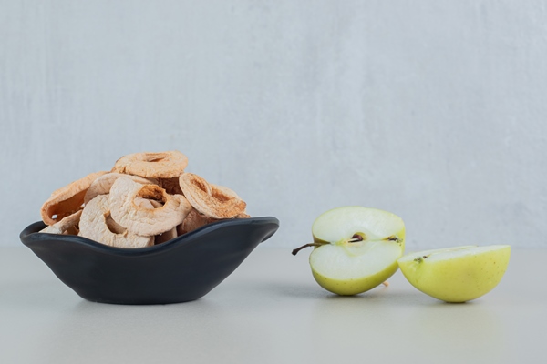 a black bowl full of dried apple fruit with slices of fresh apple - Кулинарные секреты для одиноких