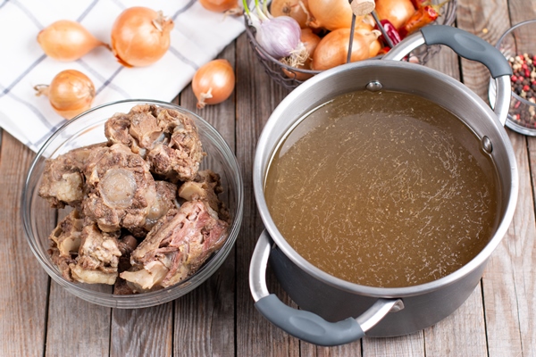 bone broth bouillon in metal saucepan on the wooden table paleo diet - Старинные секреты приготовления мясных бульонов
