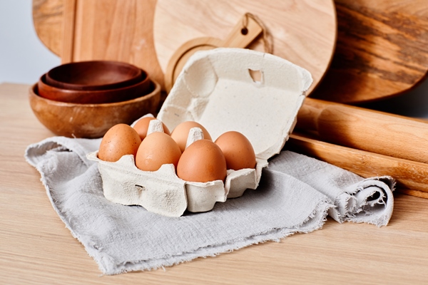 closeup of fresh raw eggs in carton on kitchen table for cooking dough with boards and rolling pin i - Секреты приготовления яиц всмятку, "в мешочек" и вкрутую. Пошаговая инструкция