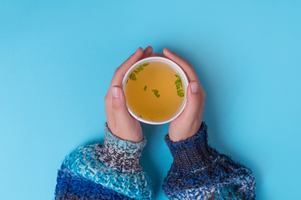 hands holding a takeaway cup with chicken broth soup - Бульон из говядины к завтраку для больного